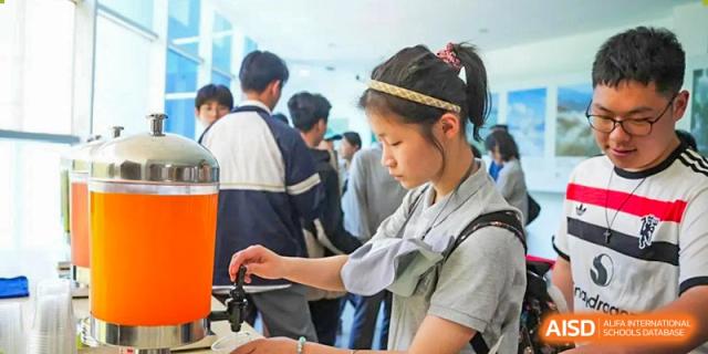 A female student in a uniform looking into a microscope during a science class at the Shanghai Jincai High School International Division.
