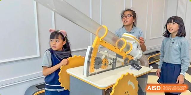 A group of students gathered around a yellow science demonstration machine in a classroom at the Shanghai Jincai High School International Division.