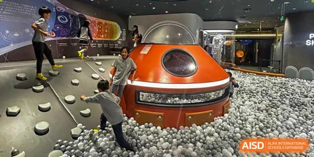 Students playing in a ball pit with a large orange futuristic car at the Shanghai Jincai High School International Division.