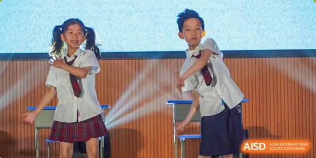 A male student performing a dance or theatrical move on a stage at the Shanghai Jincai High School International Division.