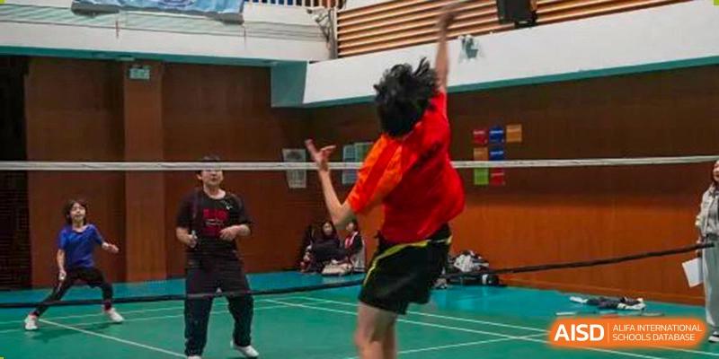 A male student with a red shirt jumping to hit a shuttlecock during a badminton game at the Shanghai Jincai High School International Division.