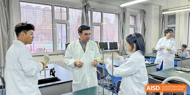 An instructor in a lab coat interacting with a male and female student inside a science laboratory setting. Canada British Colombia International Schools-Hefei.