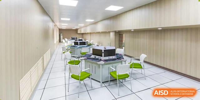 A modern, empty laboratory or classroom featuring white desks, bright green chairs, and ceiling-mounted monitors. Canada British Colombia International Schools-Hefei.