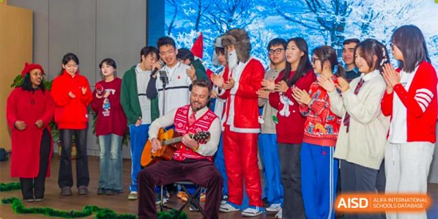 A group of students and a staff member in a Santa costume playing the guitar and singing during a festive event or holiday performance. Canada British Colombia International Schools-Hefei.