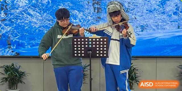 A student playing the violin with sheet music set up on a stand during a school performance. Canada British Colombia International Schools-Hefei.