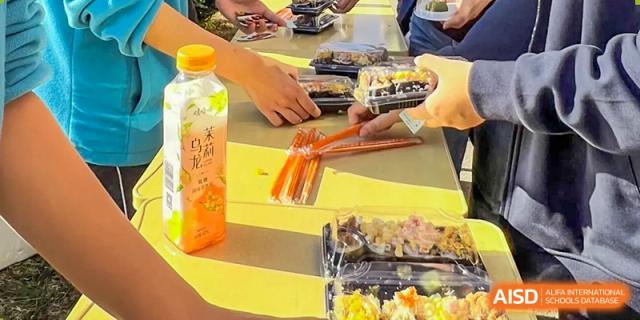 Students from Northeast Yucai Foreign Language School are getting food from a table with a variety of boxed meals.