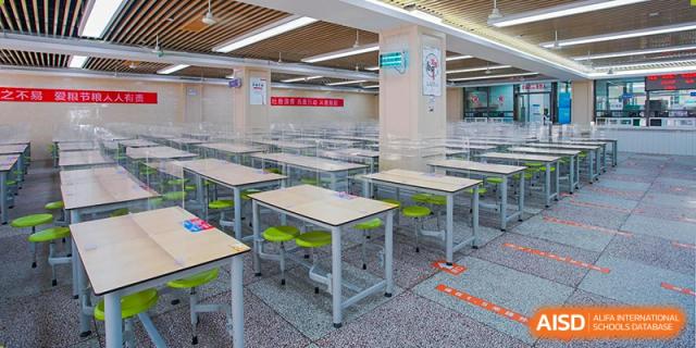 The clean, empty student dining hall or cafeteria at Wuhan Foreign Languages School International Division, with tables separated by clear plastic dividers.