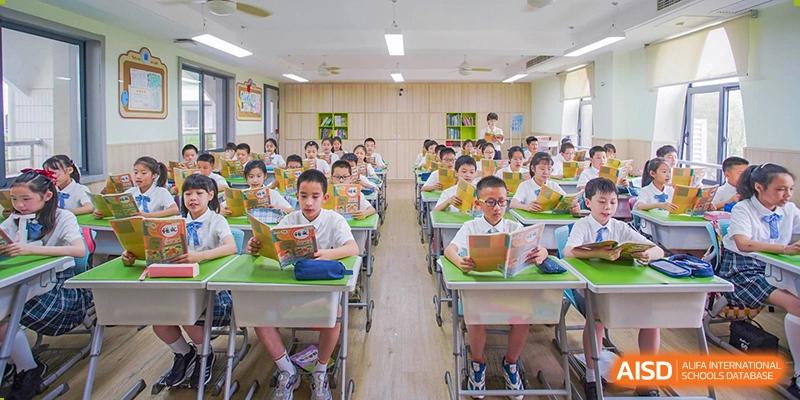 Young students from Wuhan Foreign Languages School International Division seated at desks reading in a bright classroom.