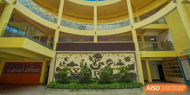 An outdoor or indoor wall mural with the word "WORLD" and decorative planting at Wuhan Foreign Languages School International Division.