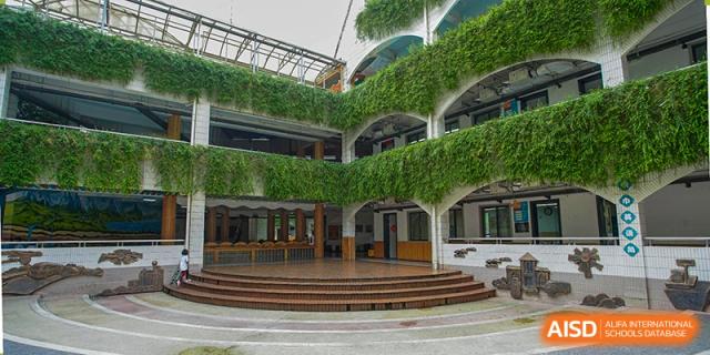 An outdoor amphitheater or performance stage with living green walls of ivy at Wuhan Foreign Languages School International Division.