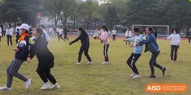 Students from Wuhan Foreign Languages School International Division playing a ball game on the grass field during a sports event.