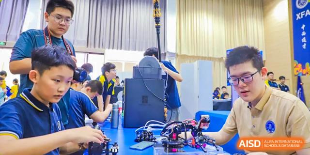 Students from Beijing Xin Fuxue International Academy work on a large robotics project in a classroom.