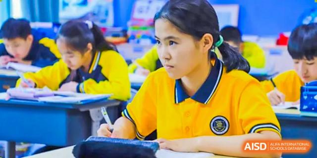 A female student from Beijing Xin Fuxue International Academy sits at her desk and focuses on her work during a class.