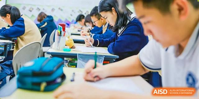 A student from Beijing Xin Fuxue International Academy works on an assignment at their desk in a classroom.