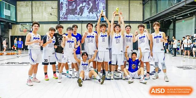 The boys' basketball team from Beijing Xin Fuxue International Academy celebrates their victory, holding a trophy and posing for a team photo.