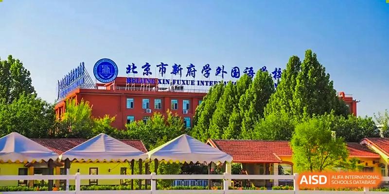 An exterior view of the main building at Beijing Xin Fuxue International Academy with a sign in Chinese visible.