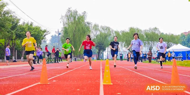 Students from Beijing Xin Fuxue International Academy run a race on an outdoor track.