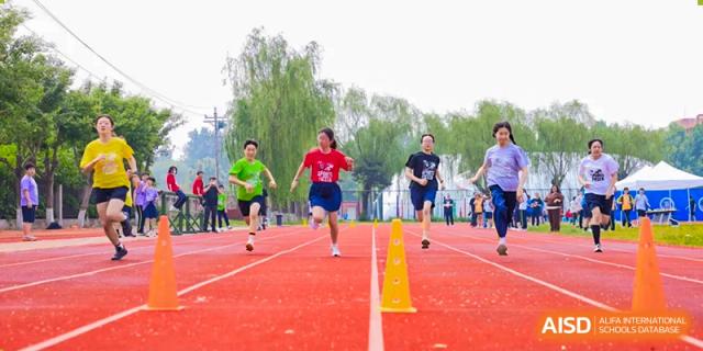 Students from Beijing Xin Fuxue International Academy run a race on an outdoor track.