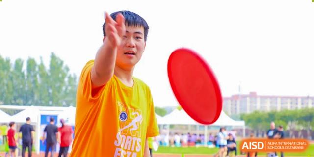 A student from Beijing Xin Fuxue International Academy prepares to throw a flying disc on the field.