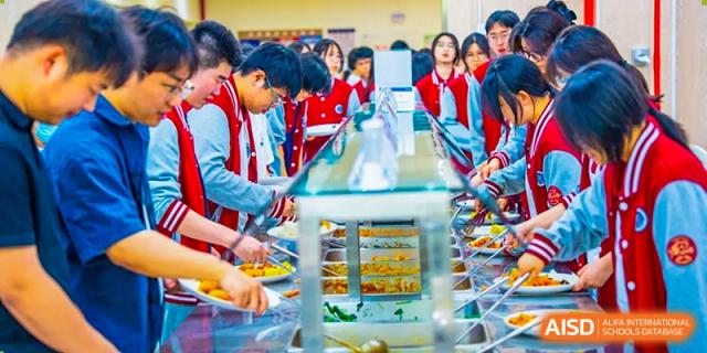 A group of students at Beijing Xin Fuxue International Academy serve themselves beverages from a dispenser.
