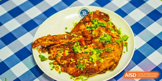 A close-up of a perfectly cooked fish fillet topped with herbs and spices, served at Beijing Xin Fuxue International Academy.