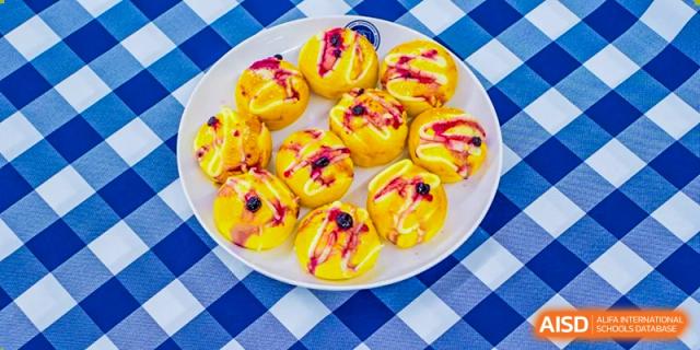 A close-up of a plate of small, fried pastries or buns with a purple filling, a snack served at Beijing Xin Fuxue International Academy.