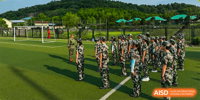 Students from The Experimental School Affiliated to Nanjing Normal University are in camouflage uniforms doing military-style training outdoors.