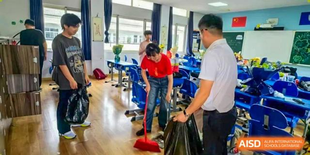 A student from Xi'an Jiaotong-Liverpool University Affiliated School (XJTLU-AS) is sweeping the classroom floor as part of a cleaning activity.