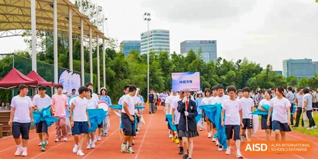 Students from Xi'an Jiaotong-Liverpool University Affiliated School (XJTLU-AS) are marching in an athletic parade, with one student holding a banner.