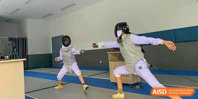Two students from Xi'an Jiaotong-Liverpool University Affiliated School (XJTLU-AS) are engaged in a fencing match, wearing full protective gear.