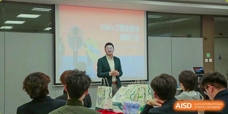 An instructor at Xi'an Jiaotong-Liverpool University Affiliated School (XJTLU-AS) is standing in front of a screen, speaking to students during a lecture or presentation.