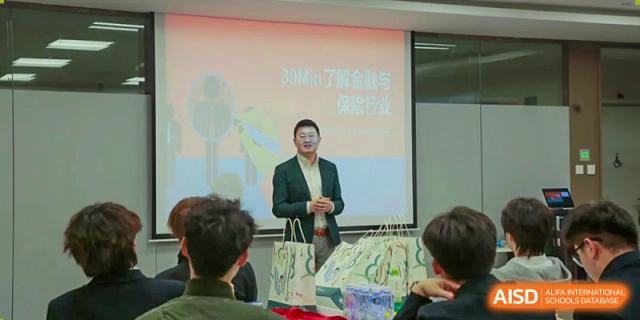 An instructor at Xi'an Jiaotong-Liverpool University Affiliated School (XJTLU-AS) is standing in front of a screen, speaking to students during a lecture or presentation.