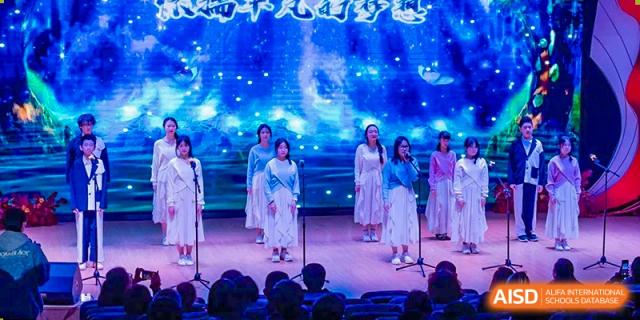 Students from Xi'an Jiaotong-Liverpool University Affiliated School (XJTLU-AS) perform a song on a brightly lit stage.
