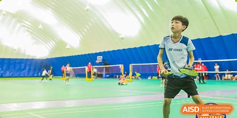 Students from Xi'an Jiaotong-Liverpool University Affiliated School (XJTLU-AS) playing badminton in a gymnasium.