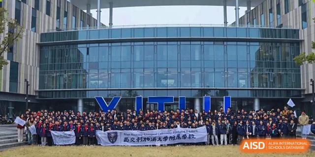 A group of students from Xi'an Jiaotong-Liverpool University Affiliated School (XJTLU-AS) holding a banner in front of a school building.