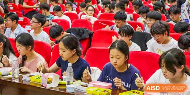 Students from Xi'an Jiaotong-Liverpool University Affiliated School (XJTLU-AS) are eating while seated in an auditorium.