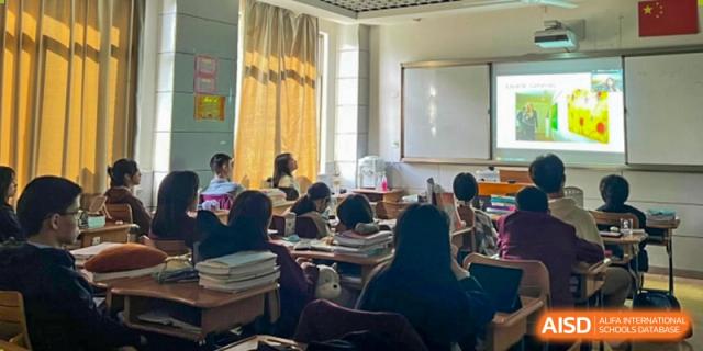 A teacher instructing a large group of students seated at desks in a classroom with large windows at Wuxi No.1 High School.