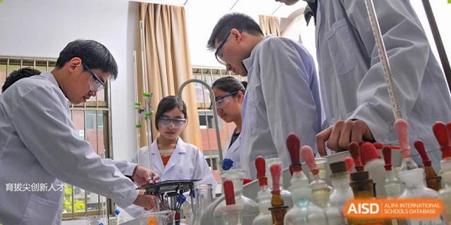 High school students wearing safety goggles and lab coats conducting an experiment in a science laboratory at Wuxi No.1 High School.