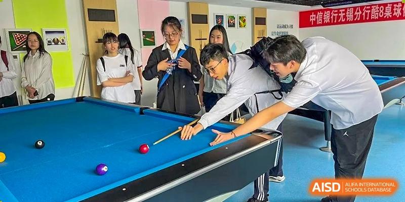 A student or teacher taking a shot during a game of billiards or pool in the school's recreational area at Wuxi No.1 High School.
