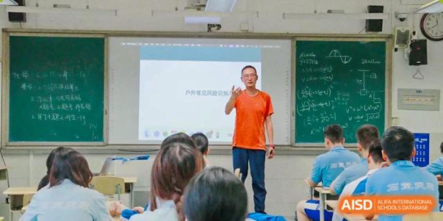 A teacher in an orange shirt gesturing while speaking to students in a classroom. Chengdu Shishi Tianfu High School International Department.