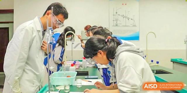 A group of students wearing safety goggles and working together on a science experiment in a lab. Chengdu Shishi Tianfu High School International Department.