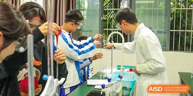 Two students wearing safety goggles working with lab equipment and beakers during a science experiment. Chengdu Shishi Tianfu High School International Department.