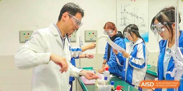 A teacher in a lab coat observing and helping a student with a science experiment. Chengdu Shishi Tianfu High School International Department.