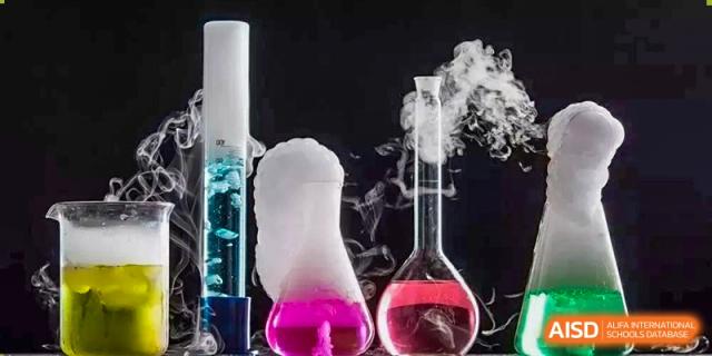 A scientific experiment in two conical flasks showing a purple liquid producing a bubbling white vapor. Chengdu Shishi Tianfu High School International Department.