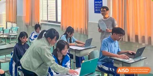 Three female students sitting at a desk and looking at a laptop computer. Chengdu Shishi Tianfu High School International Department.