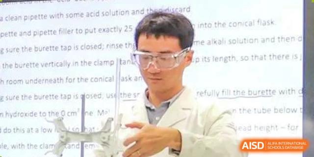 A close-up of a person wearing safety goggles, carefully handling laboratory equipment. Chengdu Shishi Tianfu High School International Department.