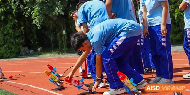Students working together on an outdoor robotics or engineering project. Chengdu Shishi Tianfu High School International Department.