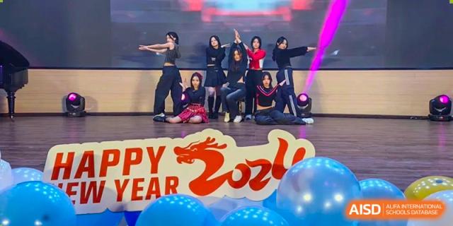 A group of students performing a synchronized dance on a stage with a banner that says "Happy New Year 2024". Chengdu Shishi Tianfu High School International Department.