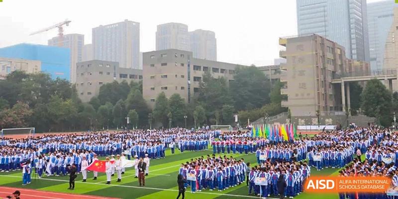 Students in blue and white uniforms gathered on a sports field during an outdoor school event. Chengdu Shishi Tianfu High School International Department.