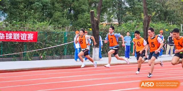 Two male students in athletic gear competing in a running race on a track. Chengdu Shishi Tianfu High School International Department.
